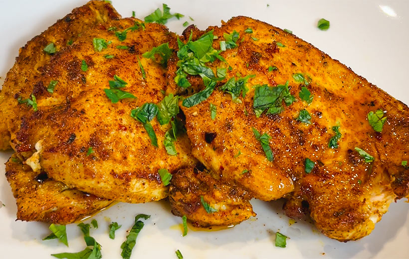 Two chicken breasts beautifully seared with Mediterranean spice blend "Grill Thrill". Topped with chopped parsley garnish.