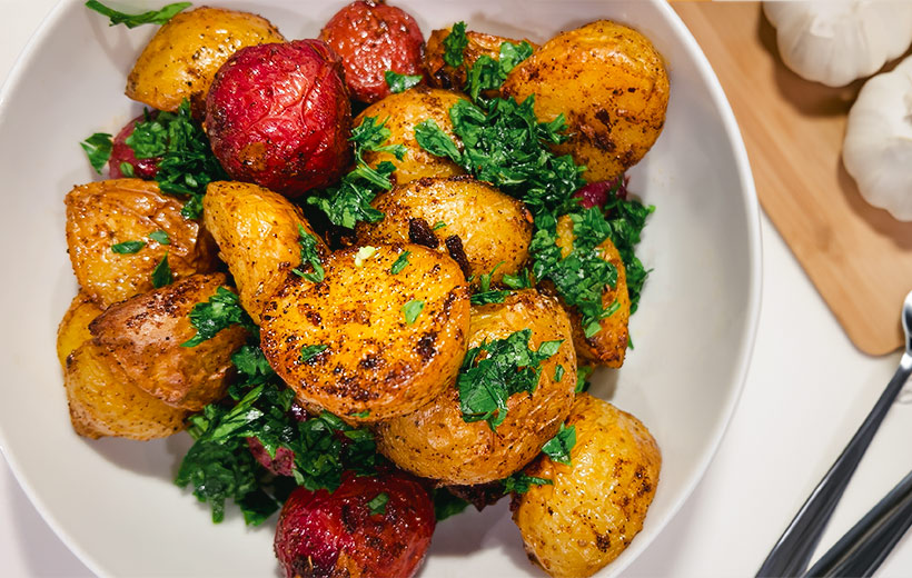 Bowl with beautiful roasted potatoes made with Mediterranean spice blend "Potayto-Potahto". Garnished with chopped parsley.