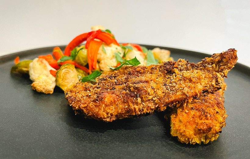 A plate with two pieces of perfect Schnitzel made with Mediterranean "Schnitz'em" spice blend. Next to it, colorful roasted vegetables.