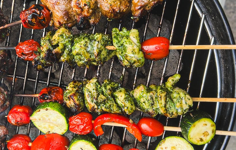 top of a BBQ grill with shish kebabs. in the center chicken shish kebabs coated with delicious beautiful herby marinade.